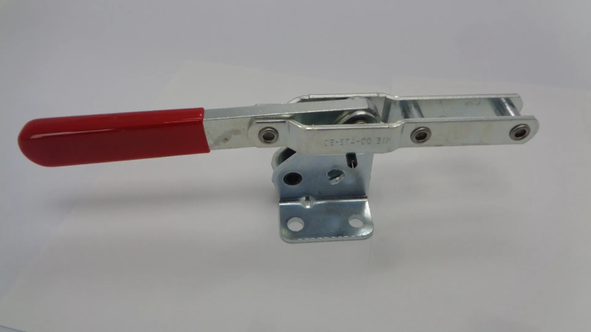 A metal toggle clamp with a red handle.