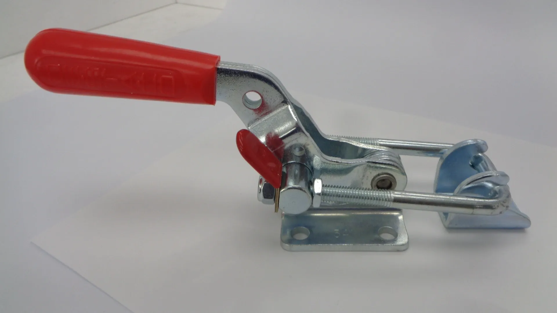 Close-up of a metal toggle clamp with red handles.