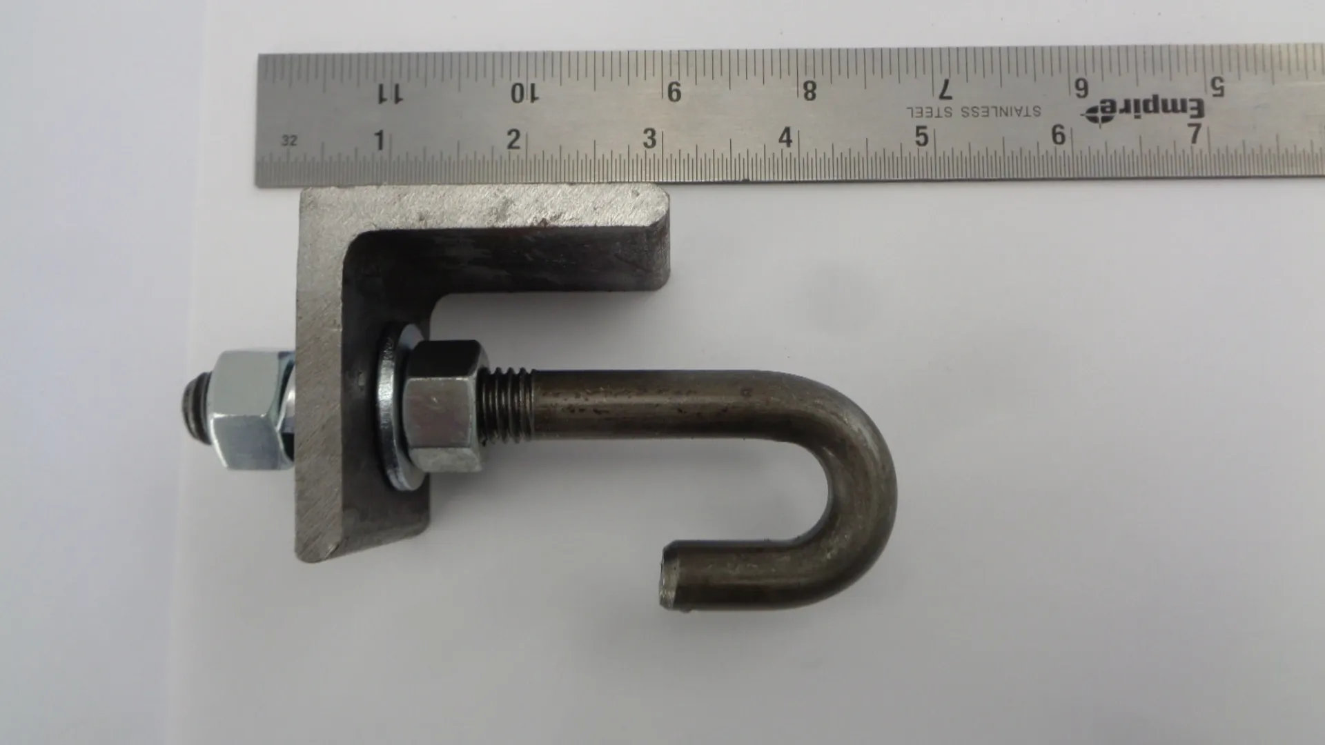 Metal L-shaped bracket with a hooked bolt and ruler for scale.