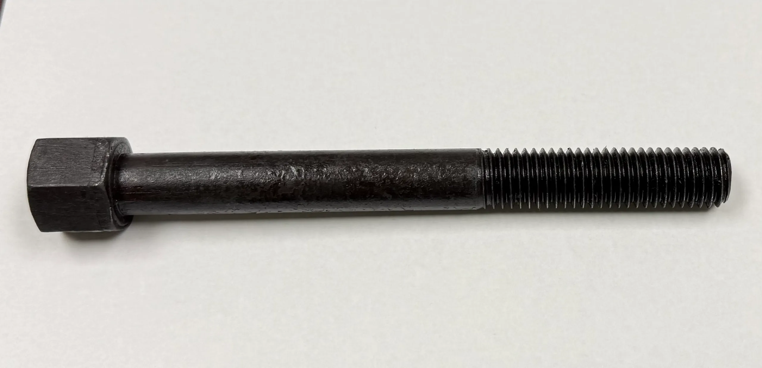 Close-up of a black threaded bolt on a white background.