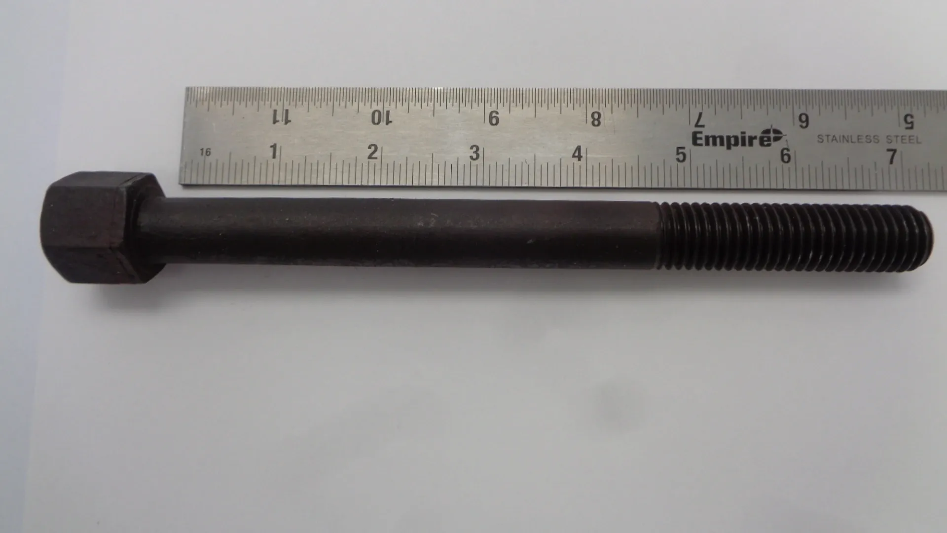 Threaded metal rod beside a ruler for measurement.