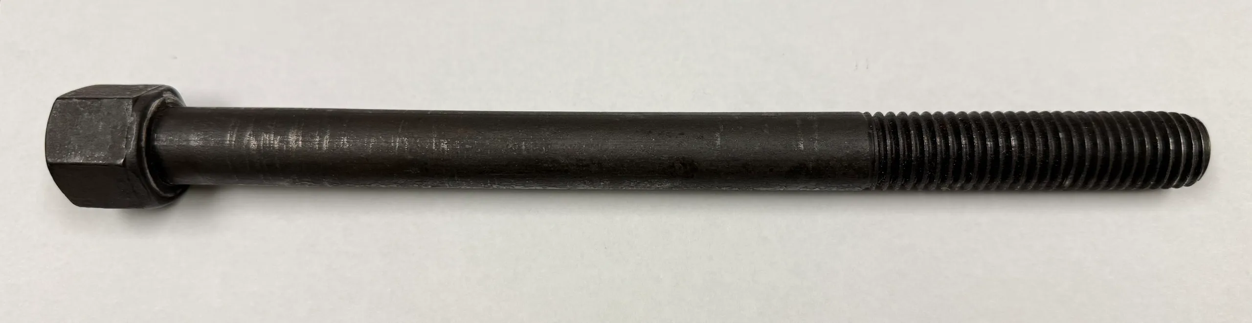 A close-up of a black cylindrical rod on a white surface.