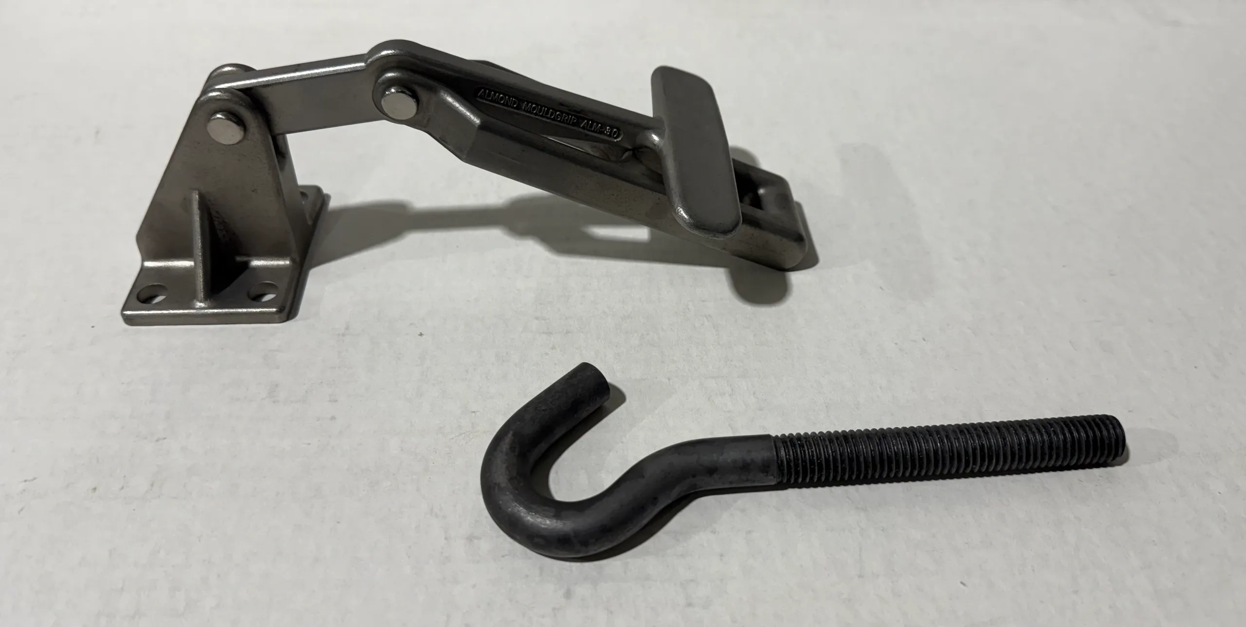 Close-up of a metal latch and a black hook on a white surface.