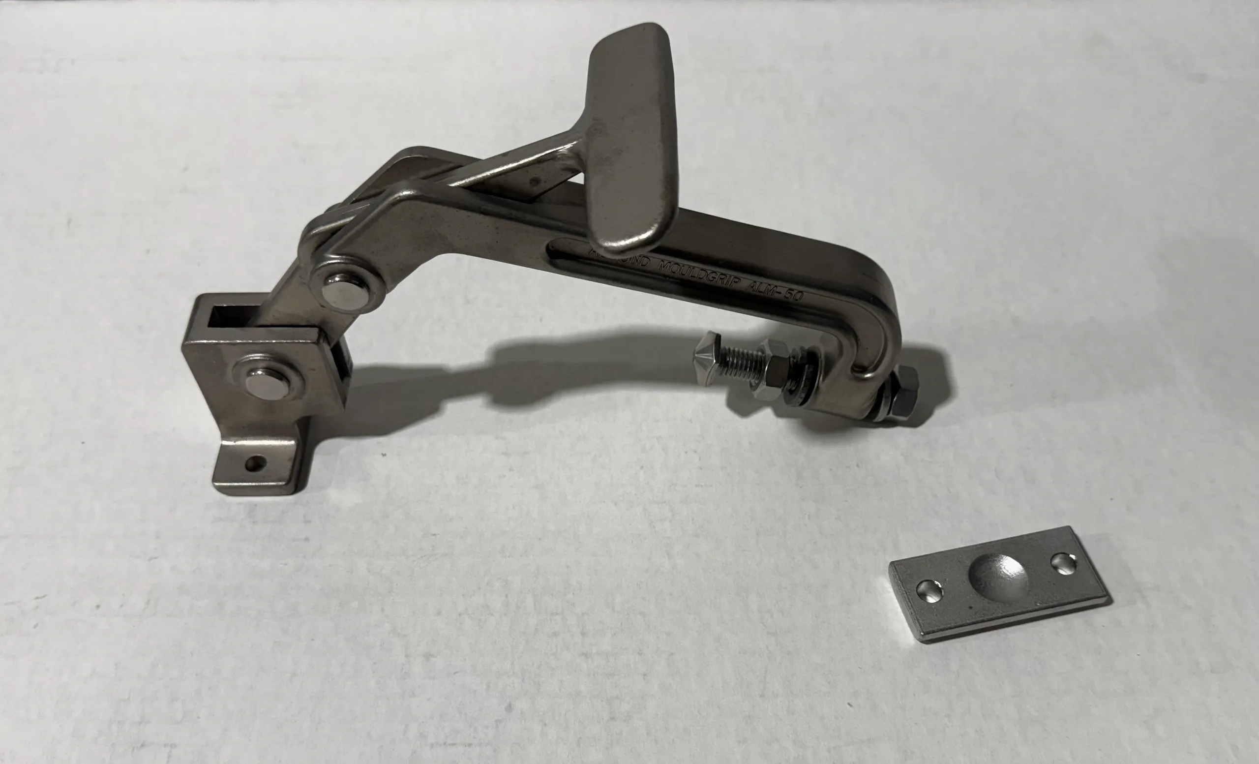 Metal mechanical hinge or latch component on a white surface.