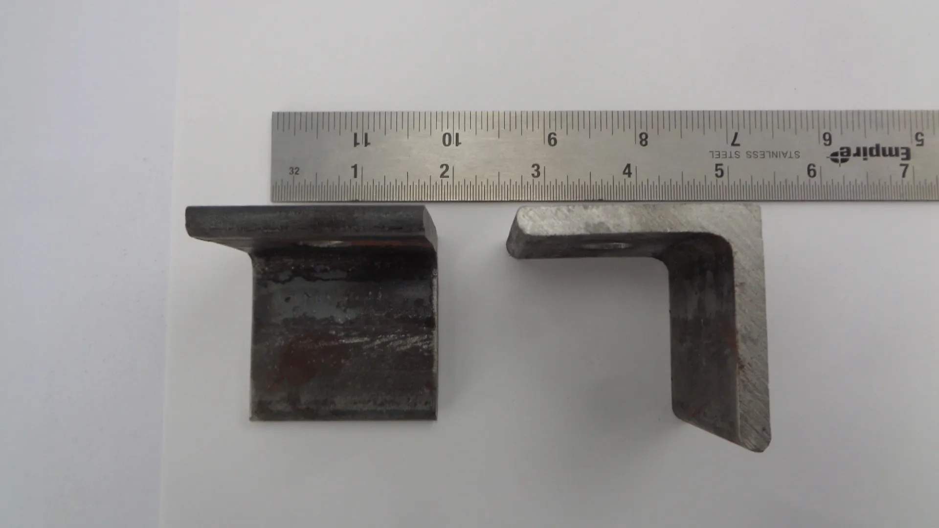 Two metal brackets with a ruler for size reference.