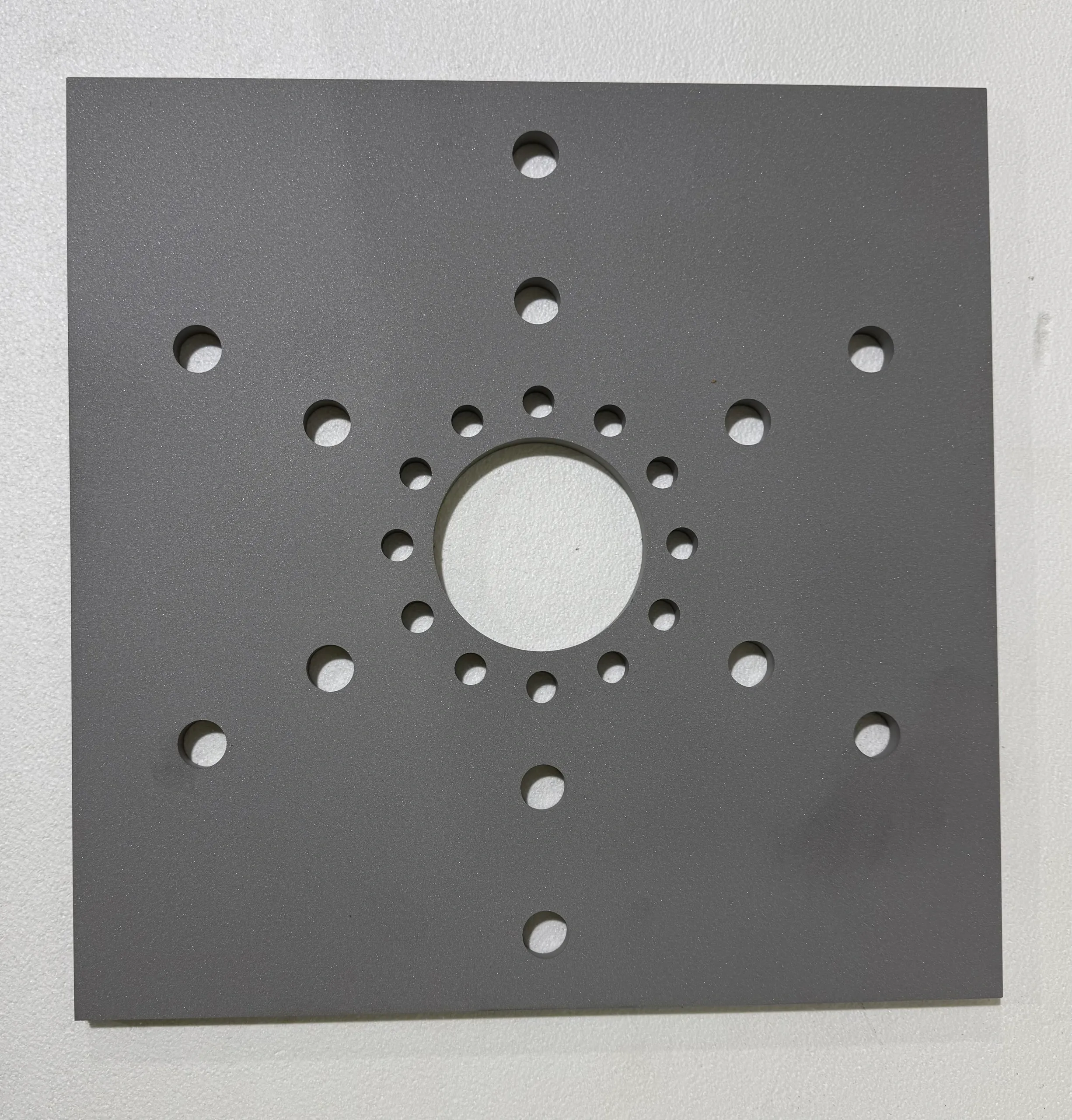 Square metal plate with circular cutouts arranged in a pattern.