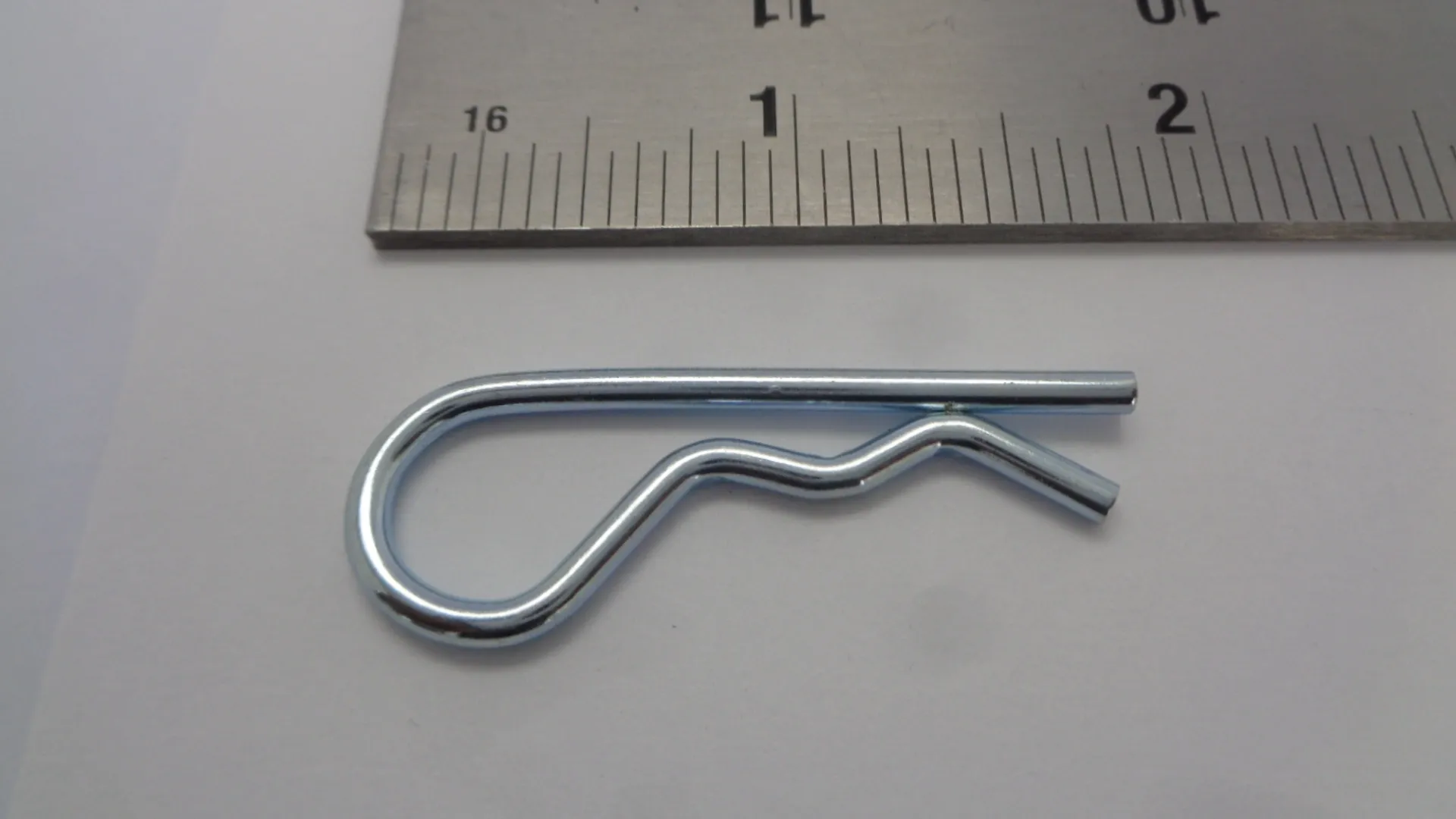 Close-up of a silver R-clip next to a ruler for size reference.