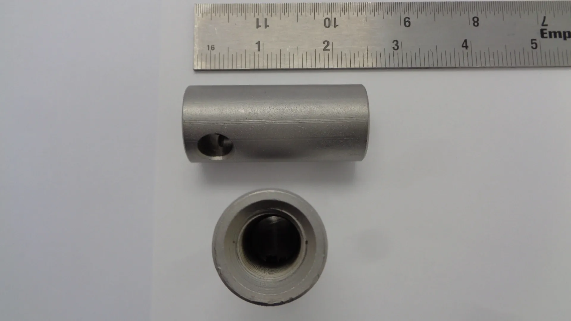Two metallic cylindrical parts with a ruler for scale.