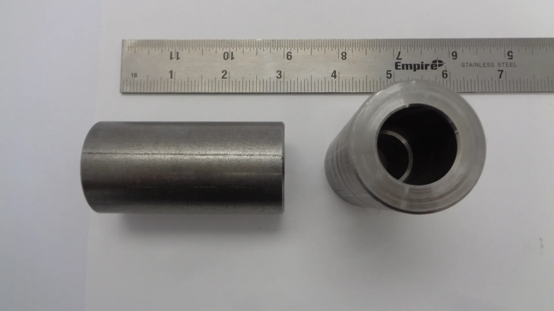 Metal tube and hollow cylindrical part next to a ruler.