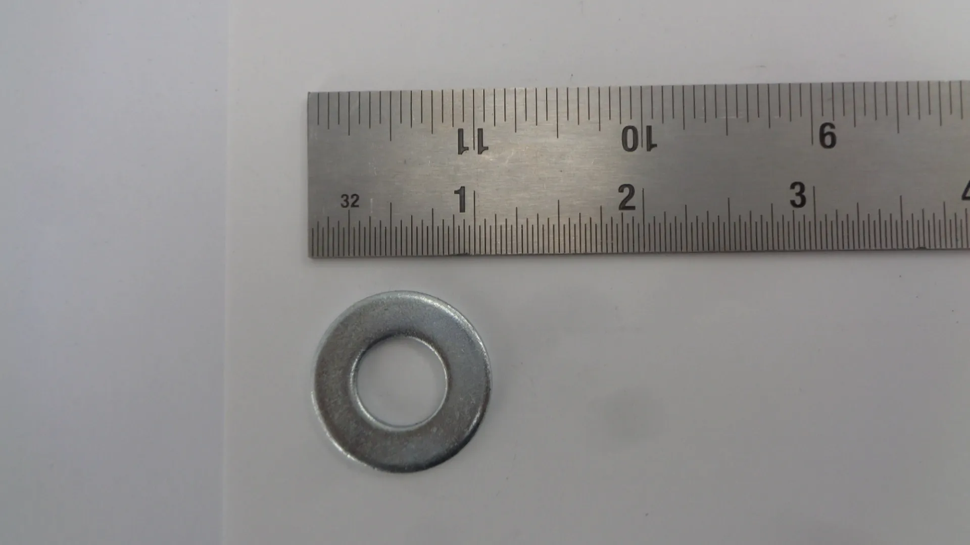 A metal washer placed below a ruler for size reference.